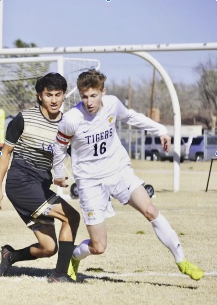 Garrett is running past a man as they play soccer